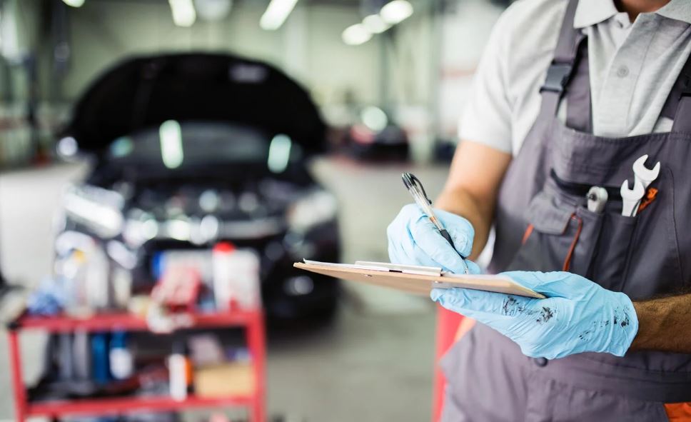 Auto service garage with technician writing on clipboard