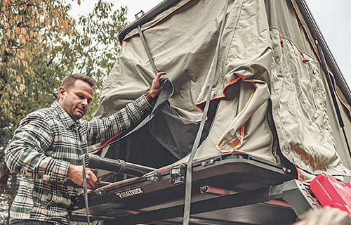 A man opening a RealTruck GoTent mounted to a GoRack